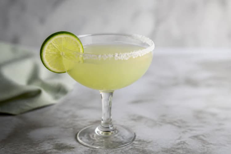 Blanco Margarita in a coupe, pale green, optional salt rim, lime wheel.