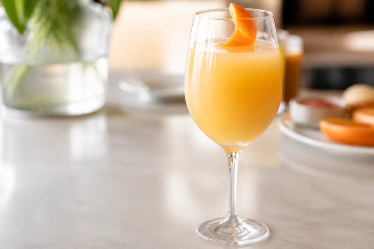 Agua de Valencia in a wine glass or flute, opaque orange, orange twist optional omit lemon.