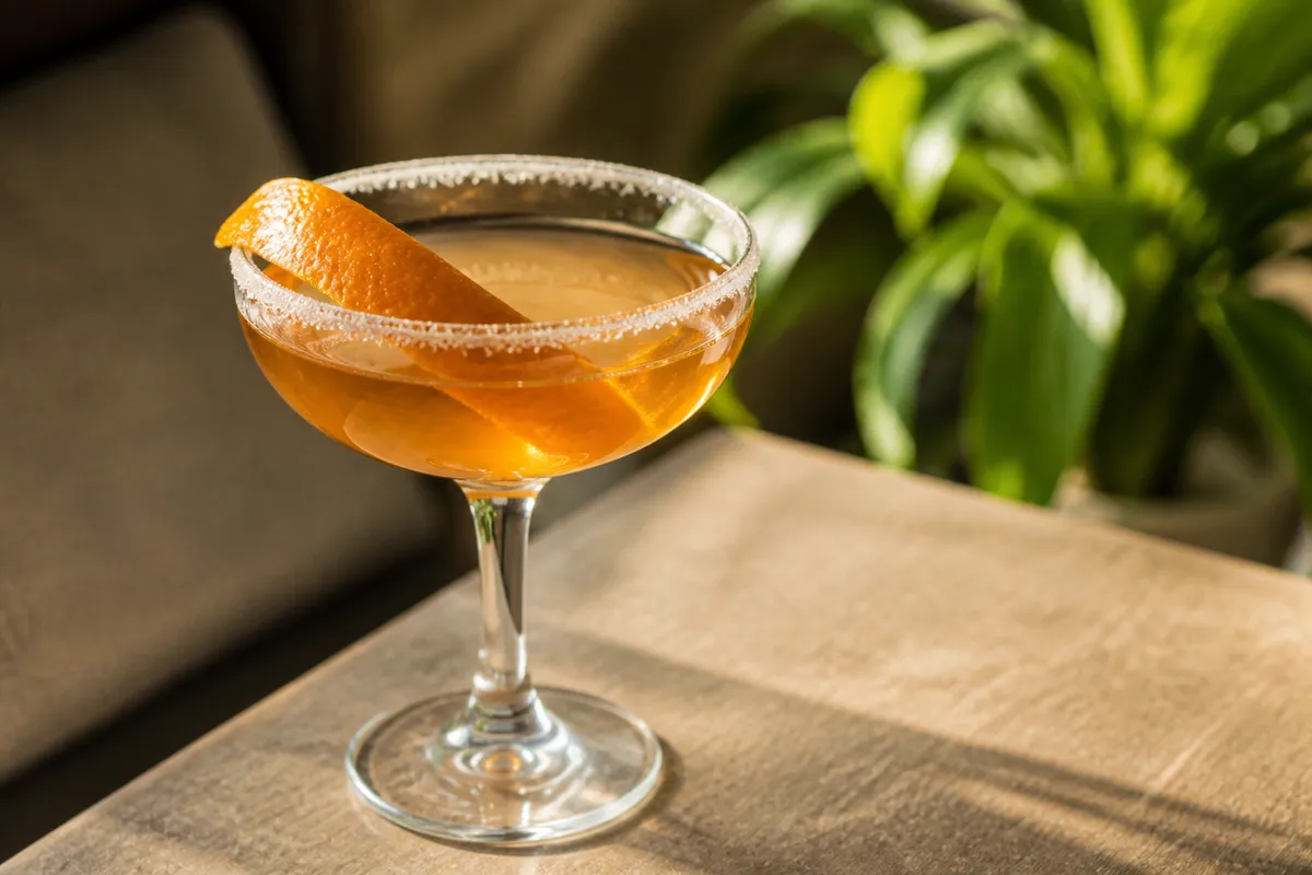Brandy Crusta in a small wine or coupe glass with sugared rim and wide citrus peel, golden.