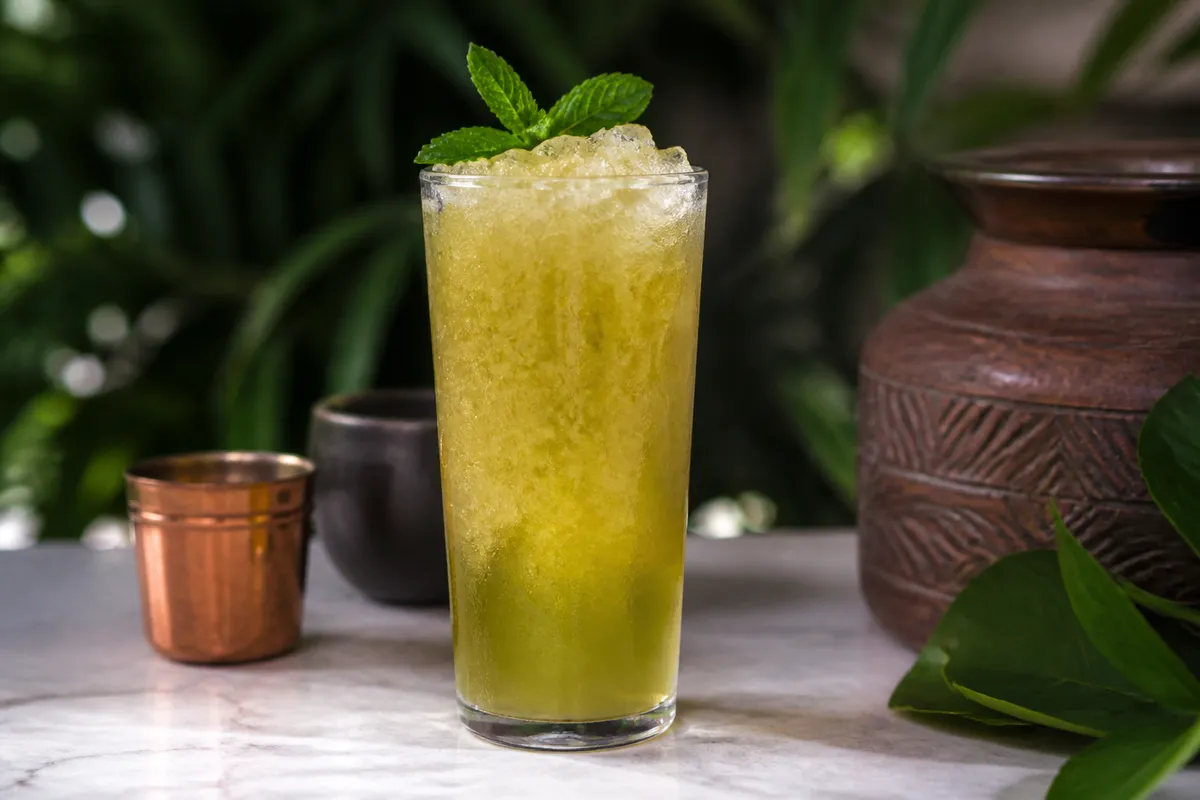 Chartreuse Swizzle in a tall glass over crushed ice, green-gold, mint garnish.