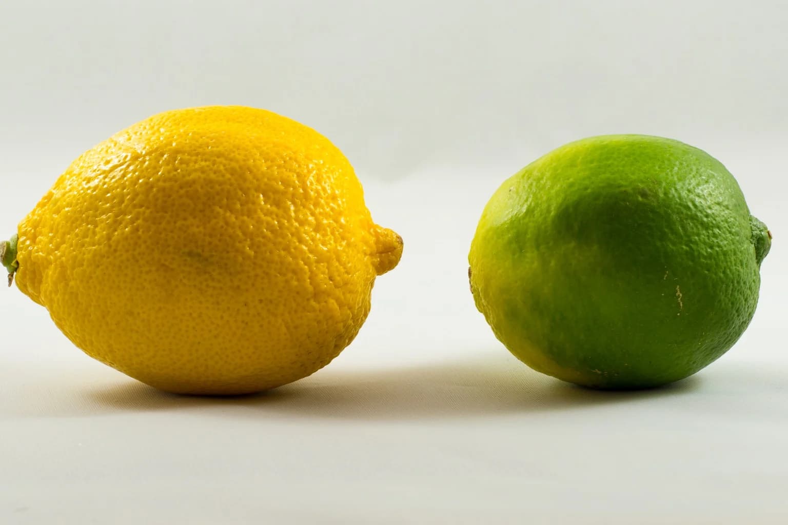 A whole lemon and lime on a light surface