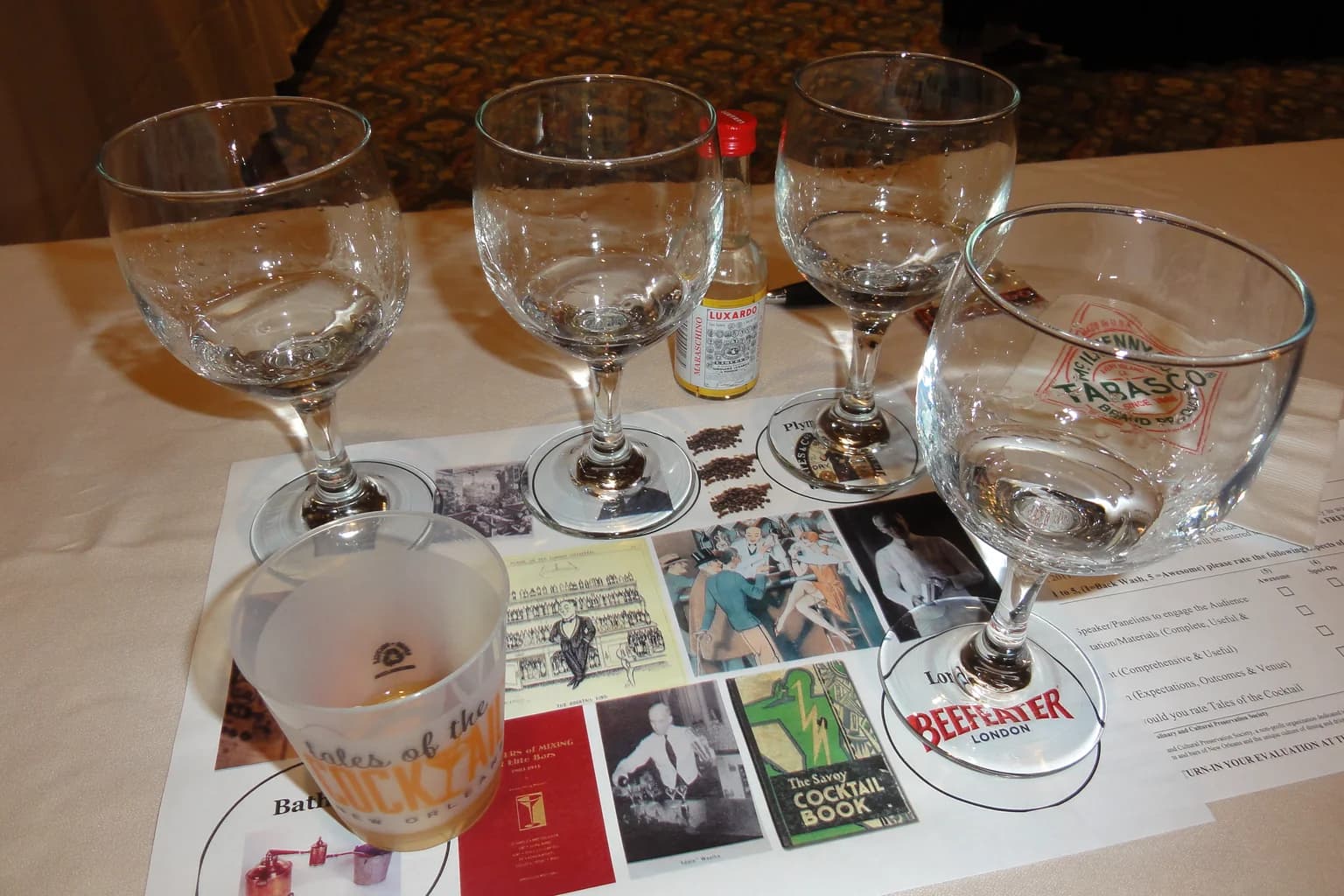 A gin tasting flight at Tales of the Cocktail — stemmed glasses on a marked mat, including Beefeater London and Plymouth