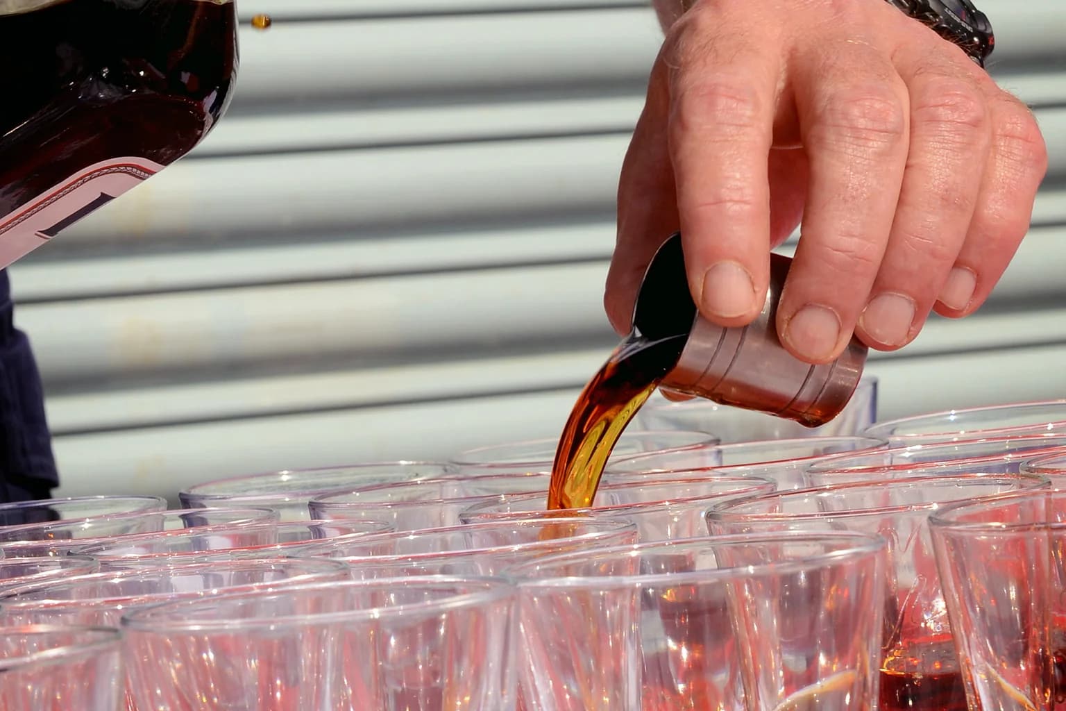 Small tasting glasses of rum being poured side by side