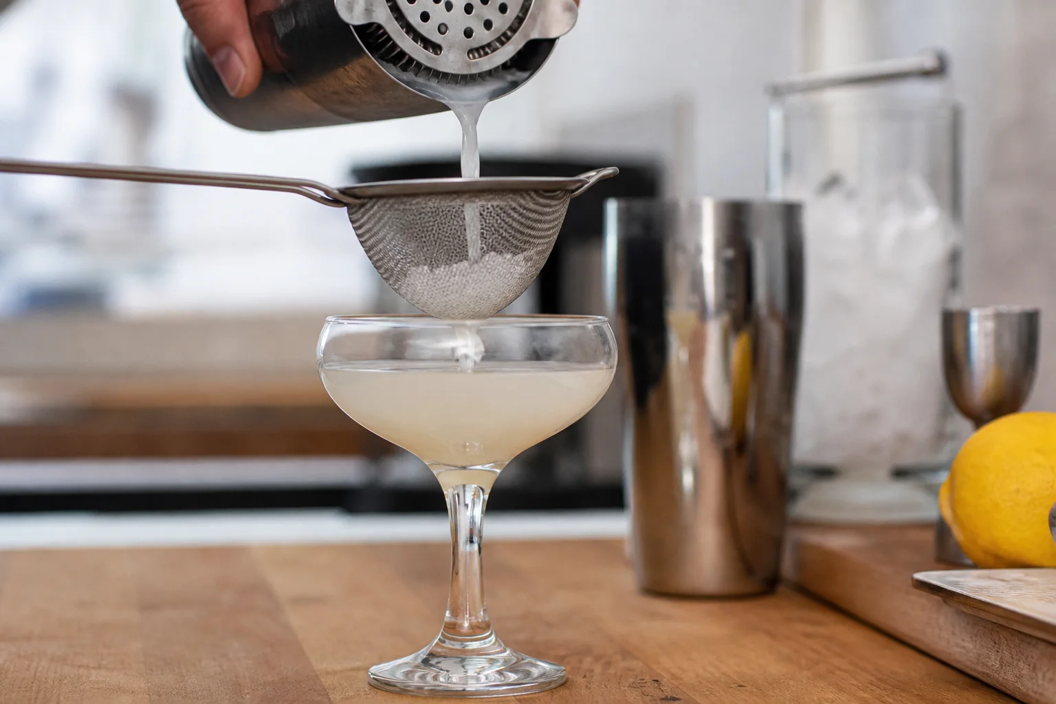 Double-straining a cocktail through fine mesh into a coupe