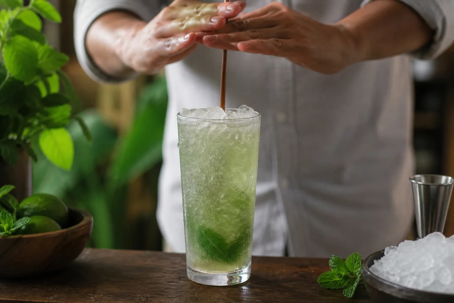 Swizzle stick spinning crushed ice in a frosted tall glass