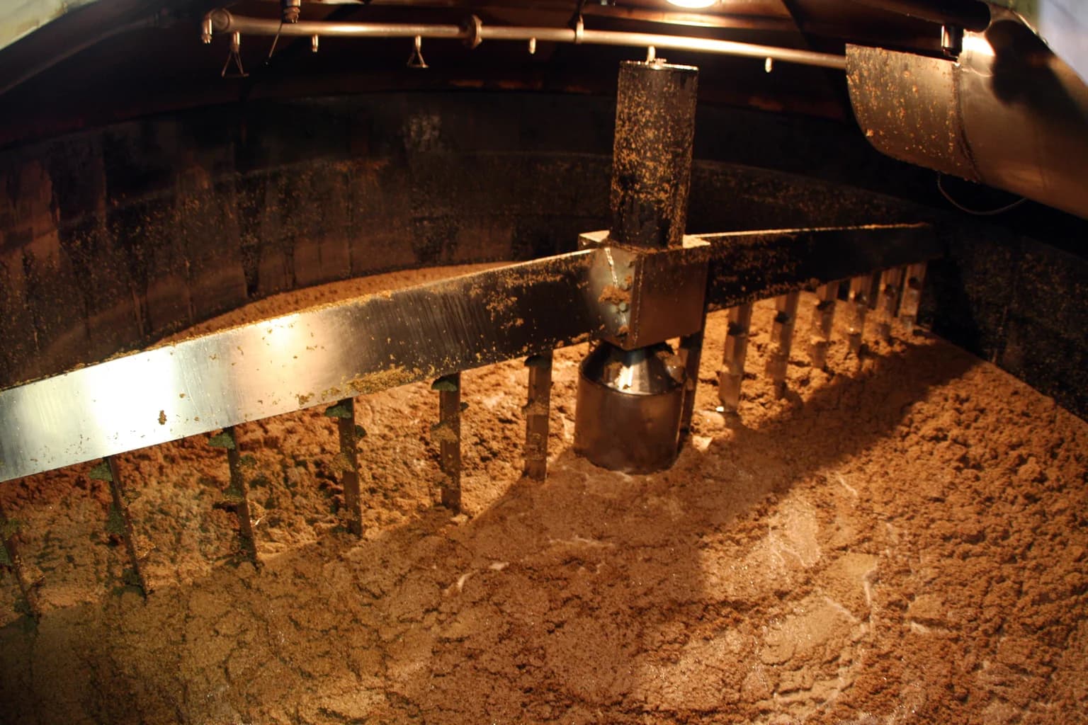 Looking down into a mash tun — grain and water under a steel rake