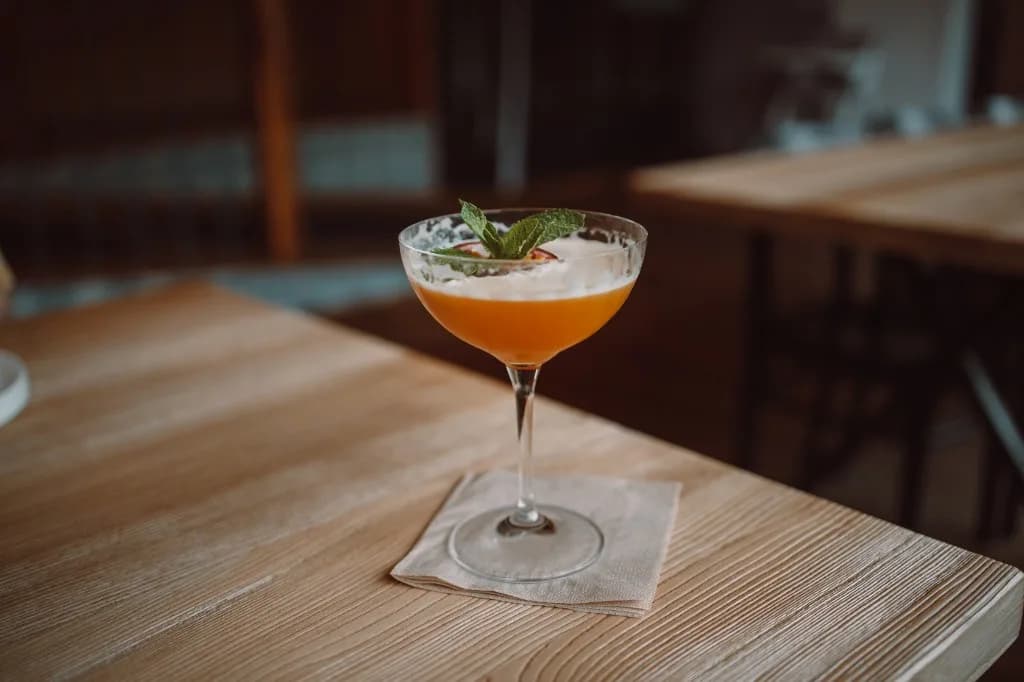 Composed coupe cocktail with mint garnish on a wooden table