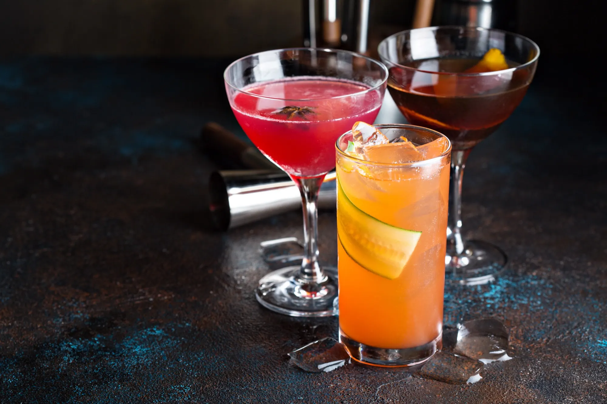 Three cocktails on a dark wood surface