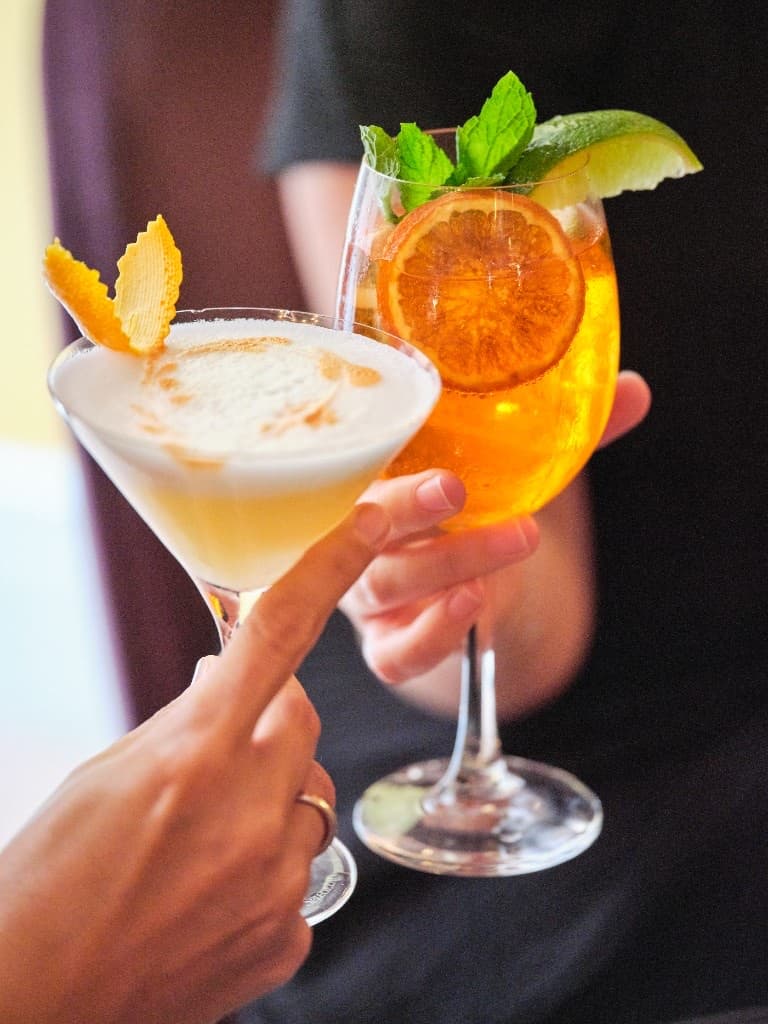 A wine glass Aperol Spritz with ice and a bright orange slice.