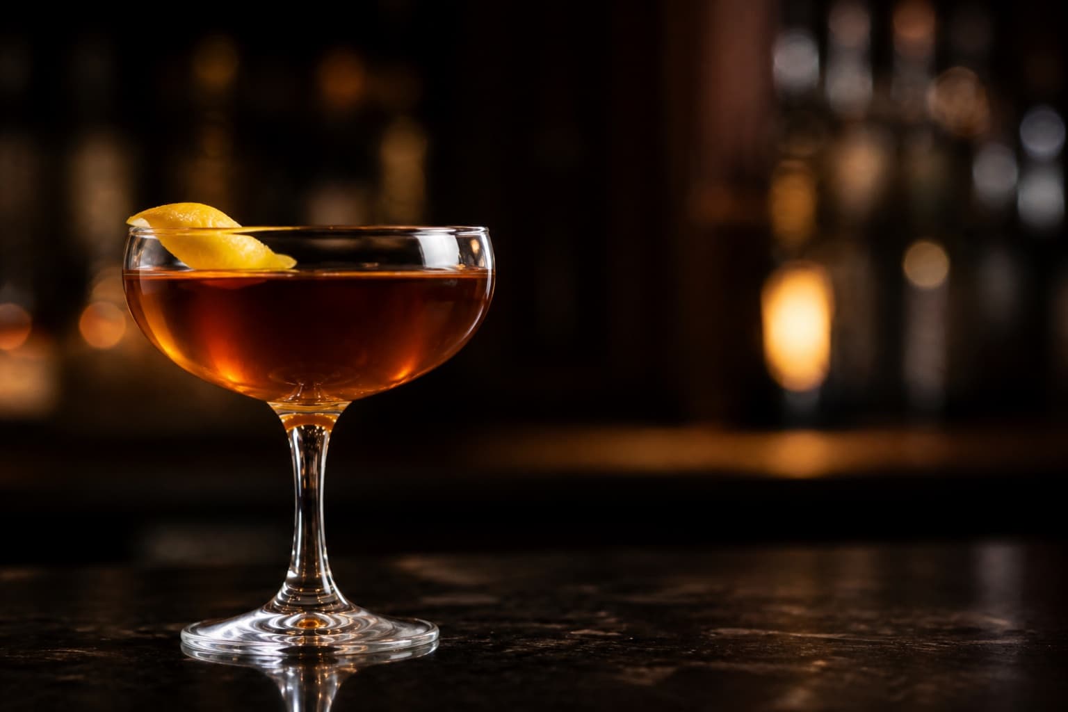 A Manhattan in a chilled coupe with a single dark cherry on a skewer resting over the rim.