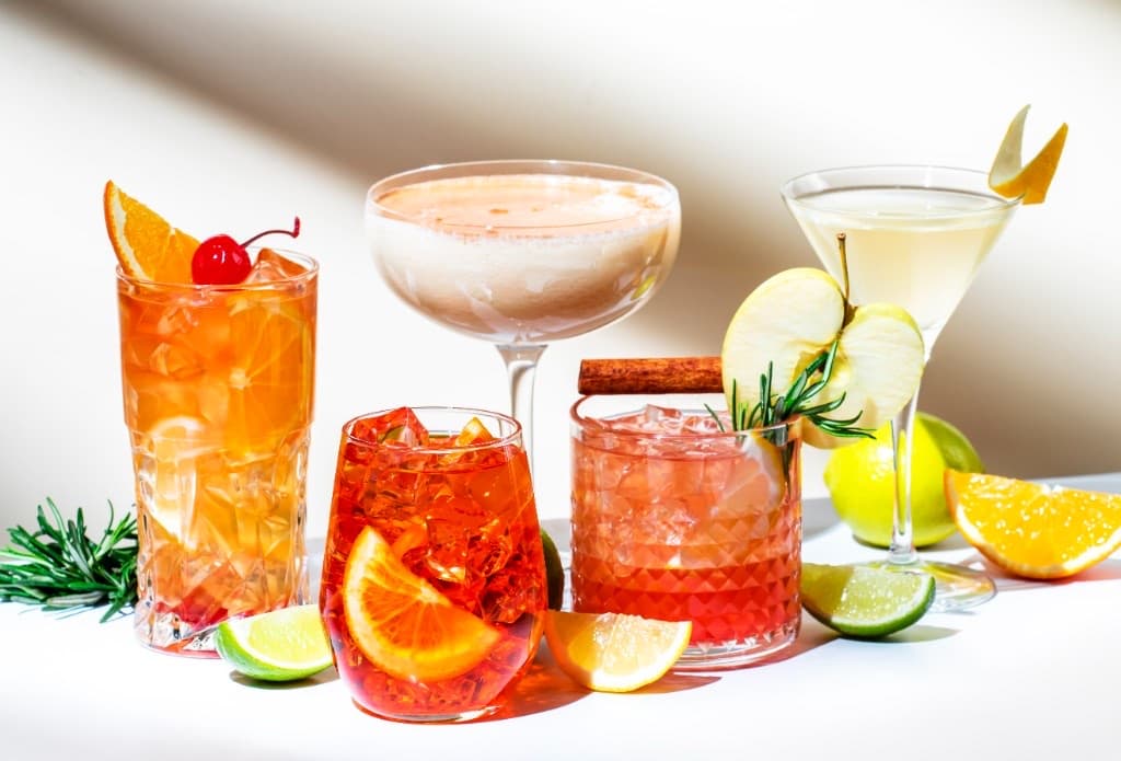Long Island Iced Tea served in a highball glass over ice, cola-tea color, garnished with a lemon wedge.