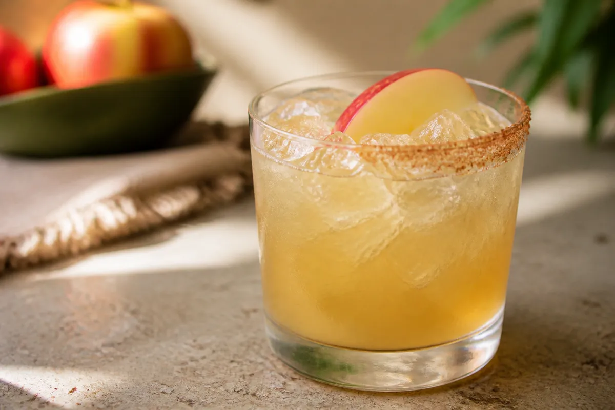 Apple Cider Margarita in a rocks glass over ice, pale gold, cinnamon-sugar rim optional.
