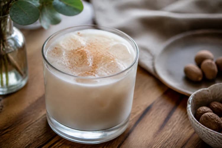 Brandy Milk Punch in a rocks glass over ice, creamy white, nutmeg dusting.
