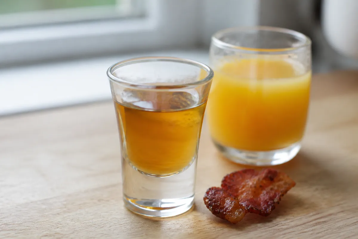 A Breakfast Shot setup with an amber shot and a small glass of orange juice.