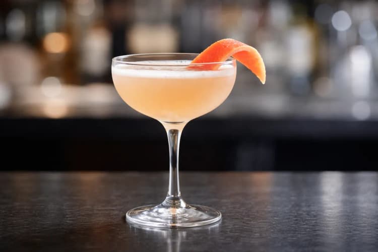 A Gibb Cocktail in a cocktail glass with a grapefruit twist.