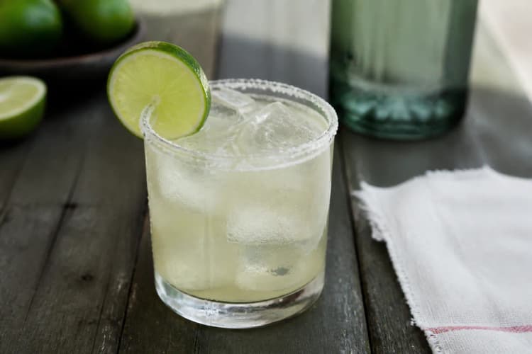 Mezcal Margarita in a rocks glass over ice, pale, lime wheel, optional salt rim.