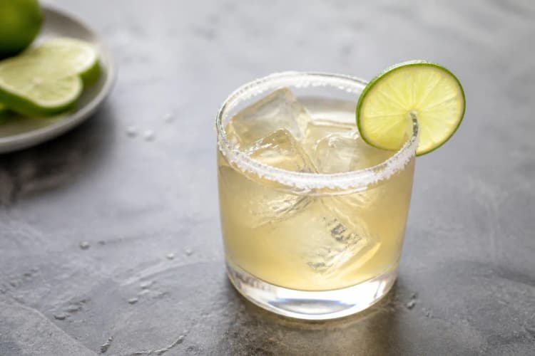 Reposado Margarita in a rocks glass over ice, pale gold, lime wheel.