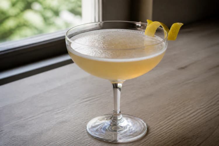 A coupe of Rum Sour with pale gold color and a lemon twist.