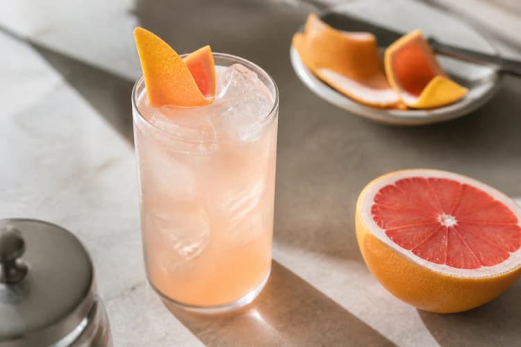 Smoke Signal in a highball over ice, pale pink, grapefruit peel.