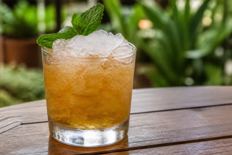 Test Pilot in a rocks glass over crushed ice, amber, mint sprig.