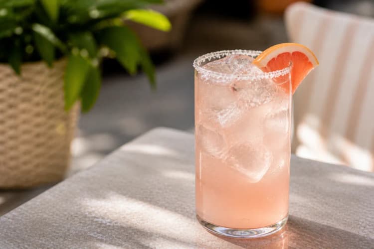 Zero-Proof Paloma in a highball over ice, pale pink grapefruit, grapefruit wedge, optional salt rim.