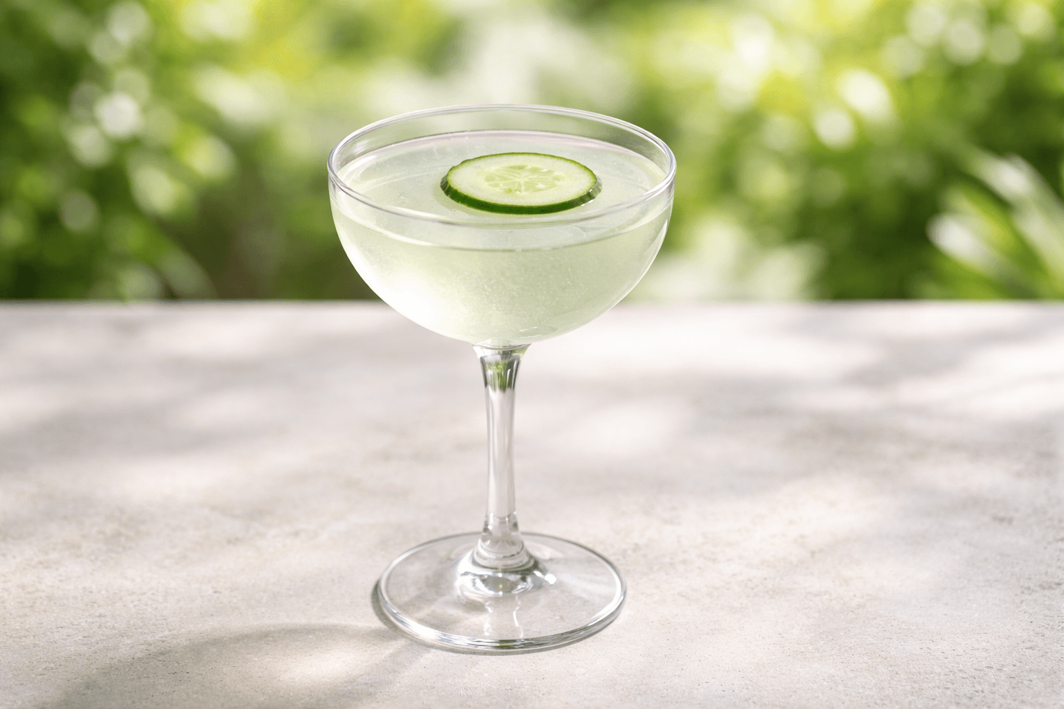 A coupe of Eastside with floating cucumber slice.