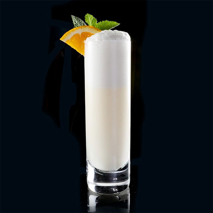 A tall Ramos Gin Fizz in a chilled Collins glass with a towering white foam head and no visible garnish.