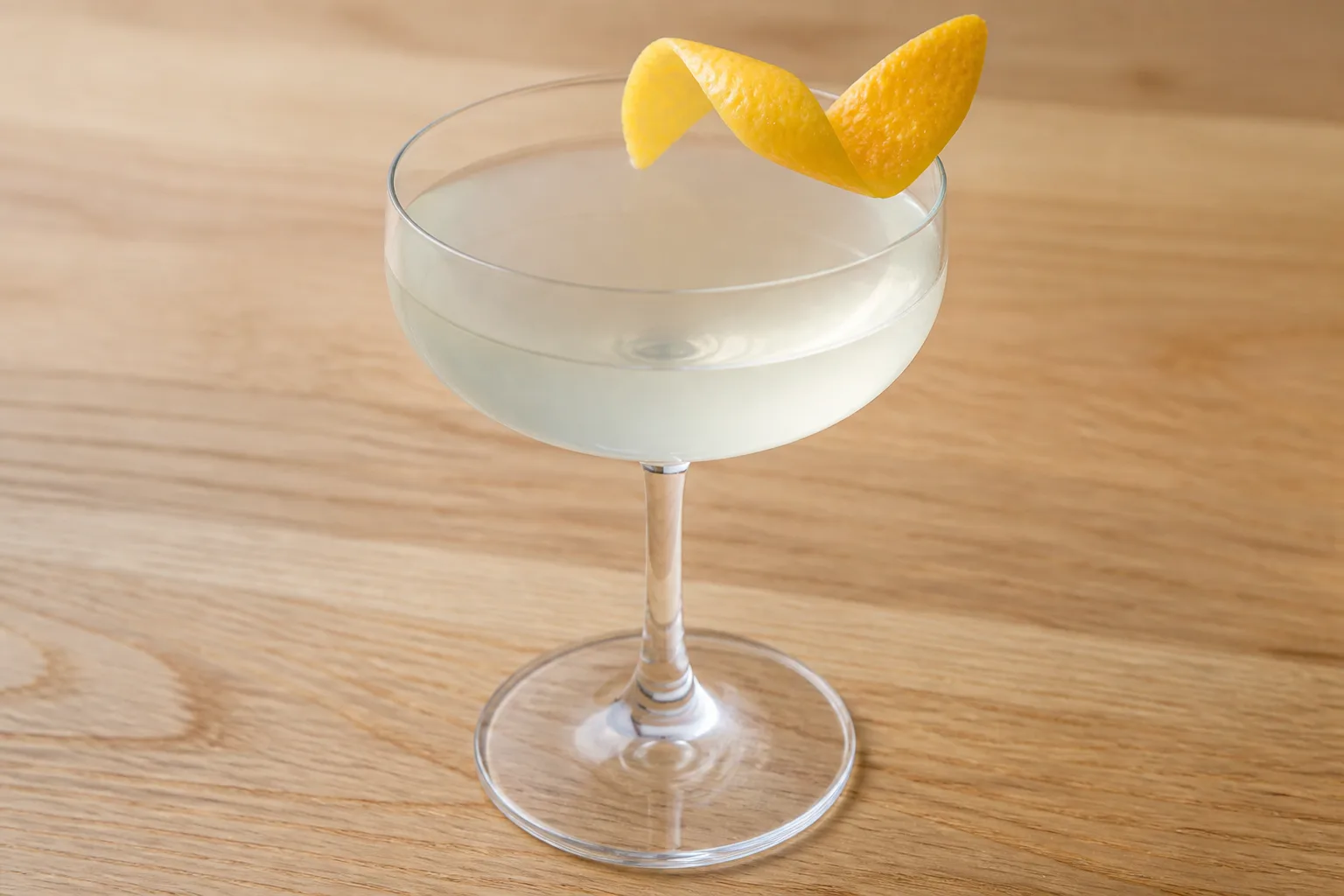 Expressing citrus peel oils over a coupe cocktail