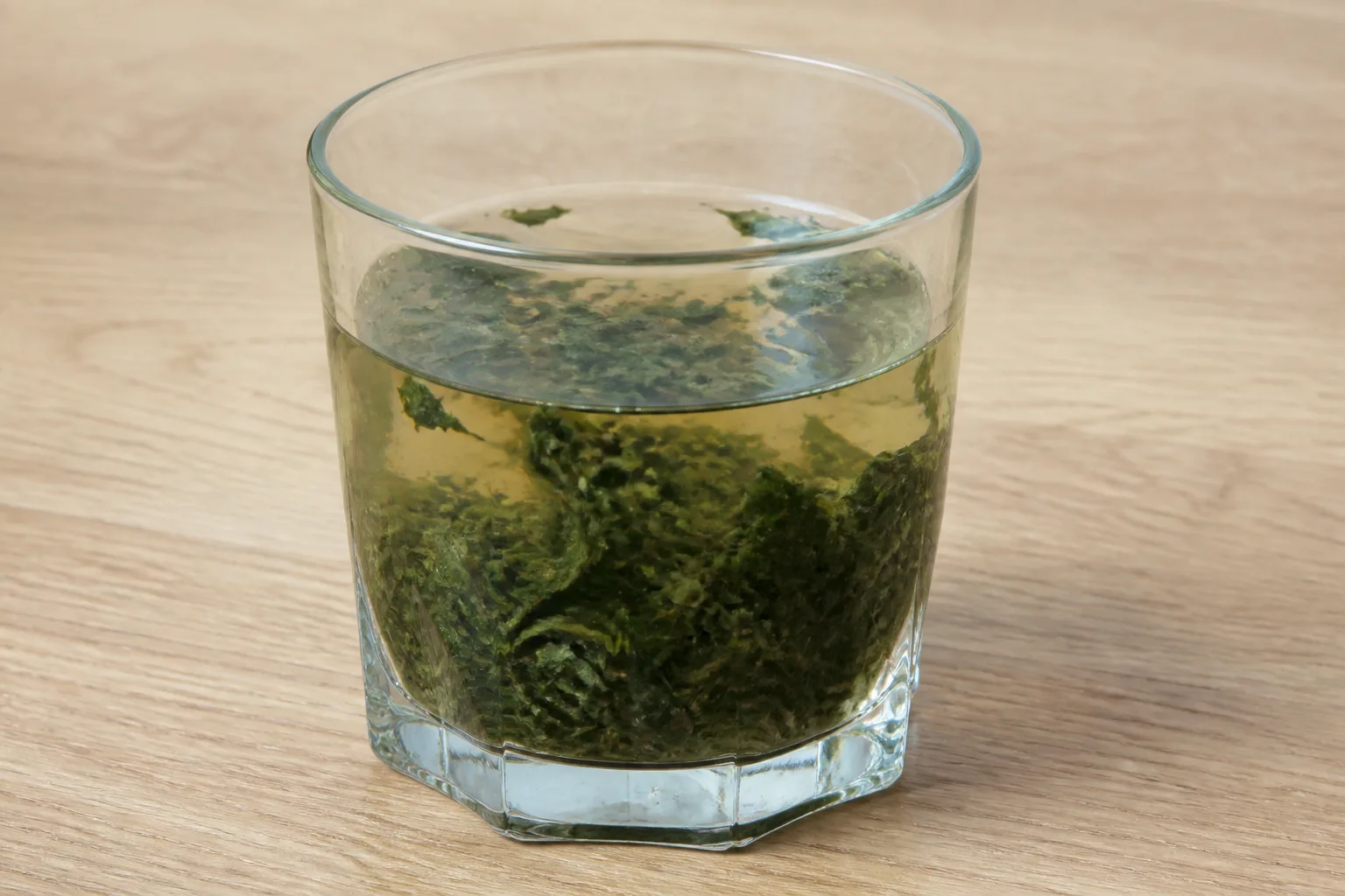 Mint being shredded and over-muddled in a glass