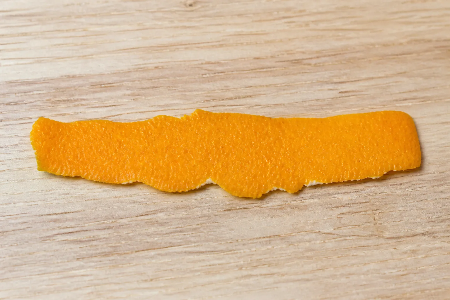 A thin strip of orange peel with minimal pith on a counter