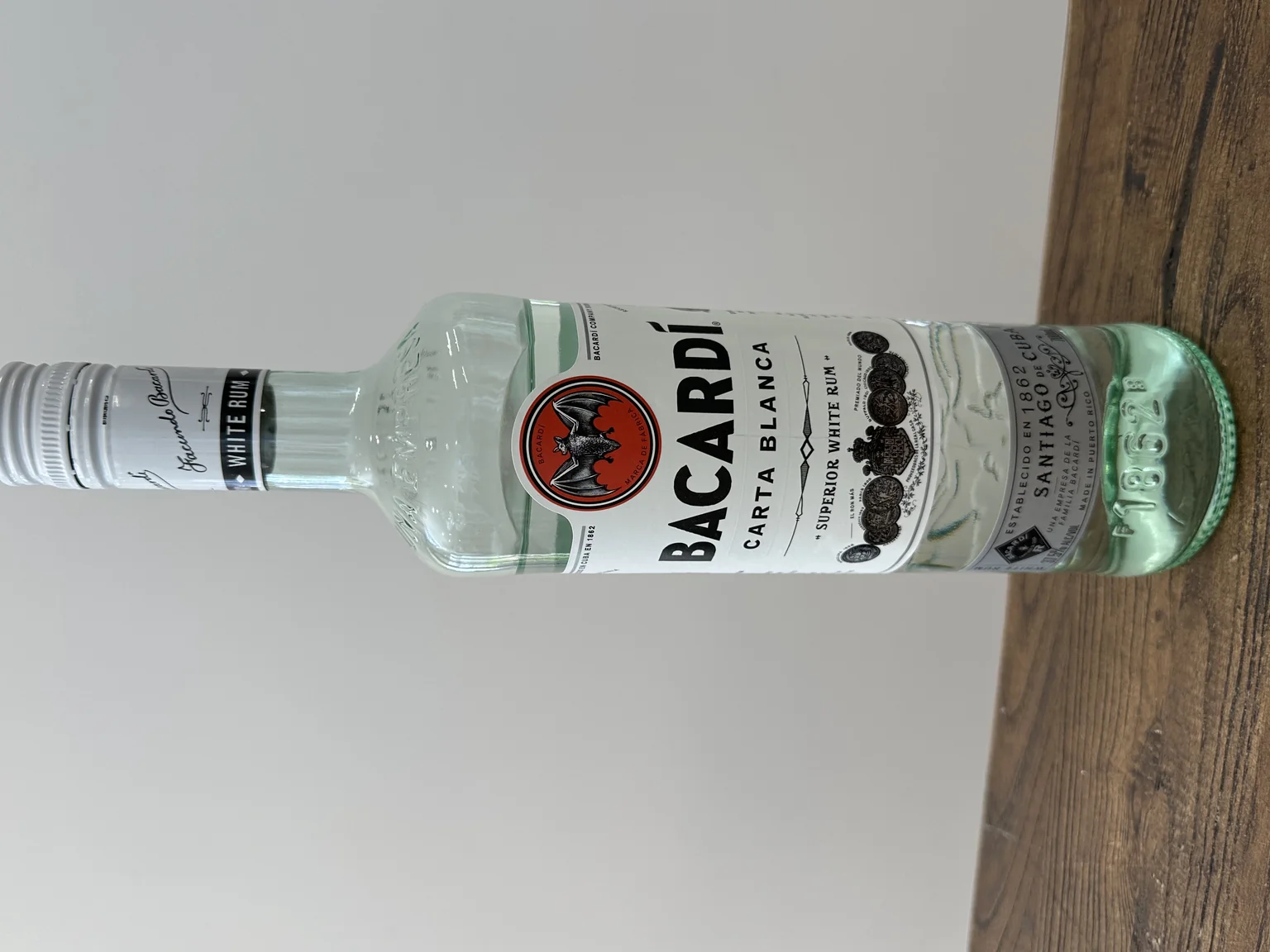 A bottle of Bacardi Carta Blanca Superior white rum lying on a wooden table