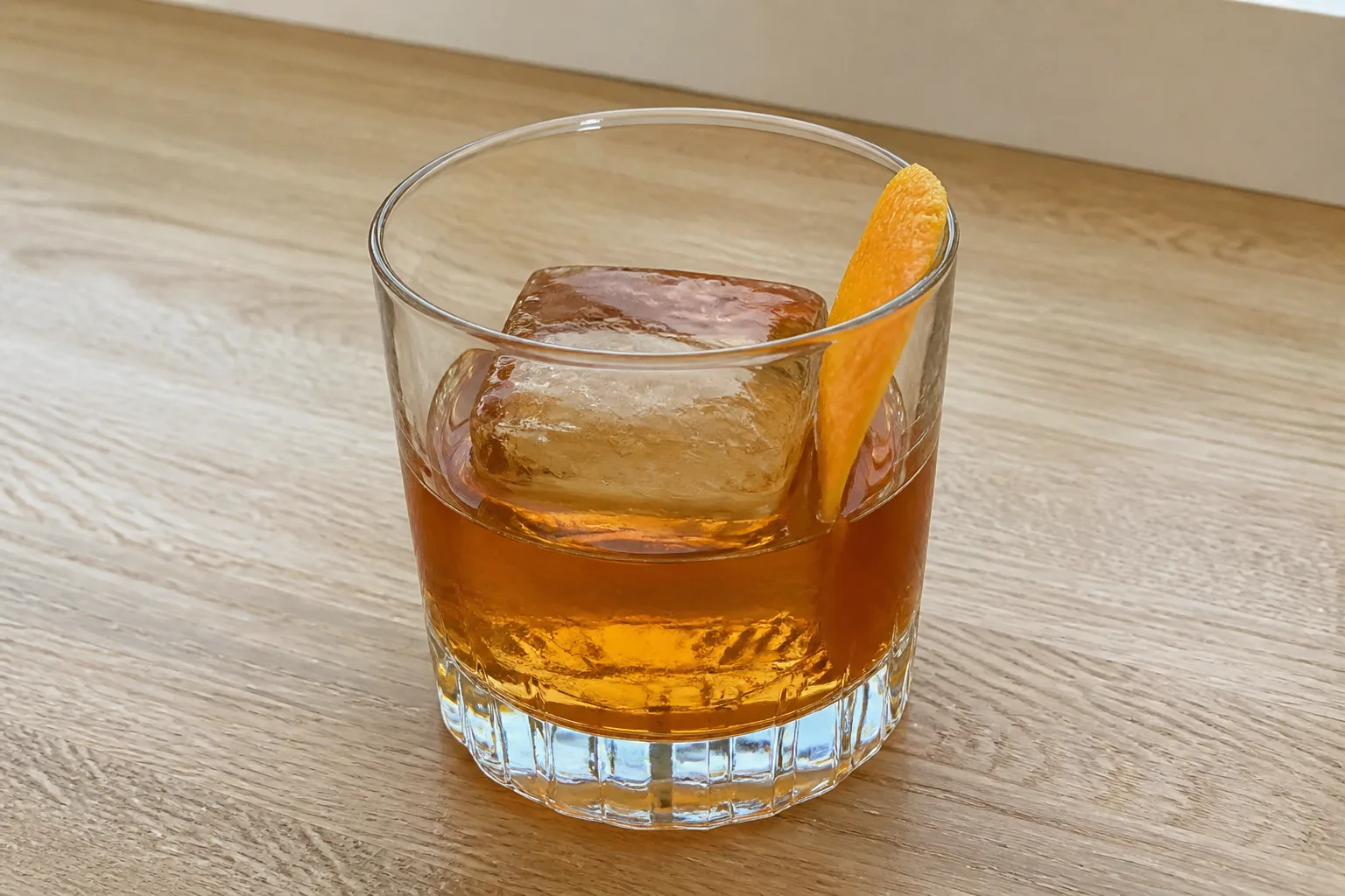 An Old Fashioned in a rocks glass with a large ice cube
