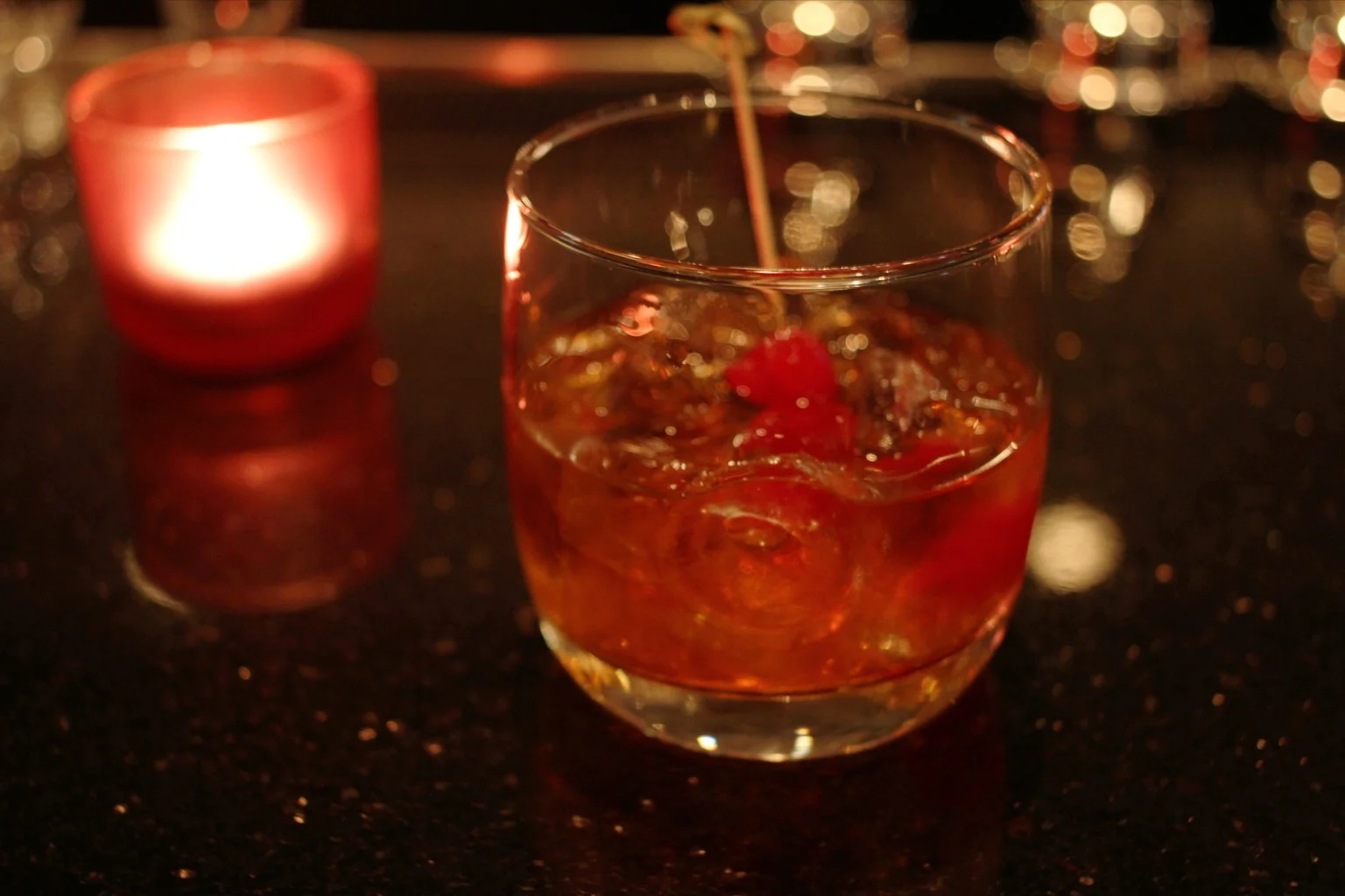 A Manhattan in a coupe with a cherry on a pick