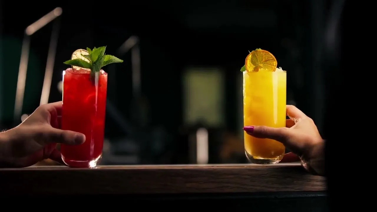 Close-up of two people cheering cocktails in a bar